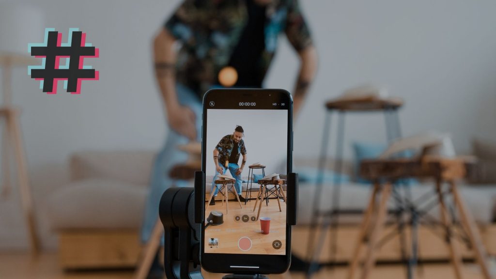 Image of a man recording himself with a mobile phone, which is the featured image of a post about the TikTok Creators Fund
