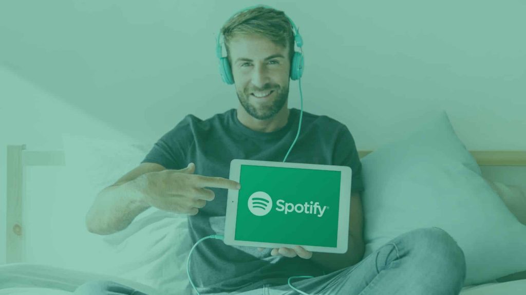 A boy showing the Spotify logo on a laptop, the cover image of the 'How to make money on Spotify' blog