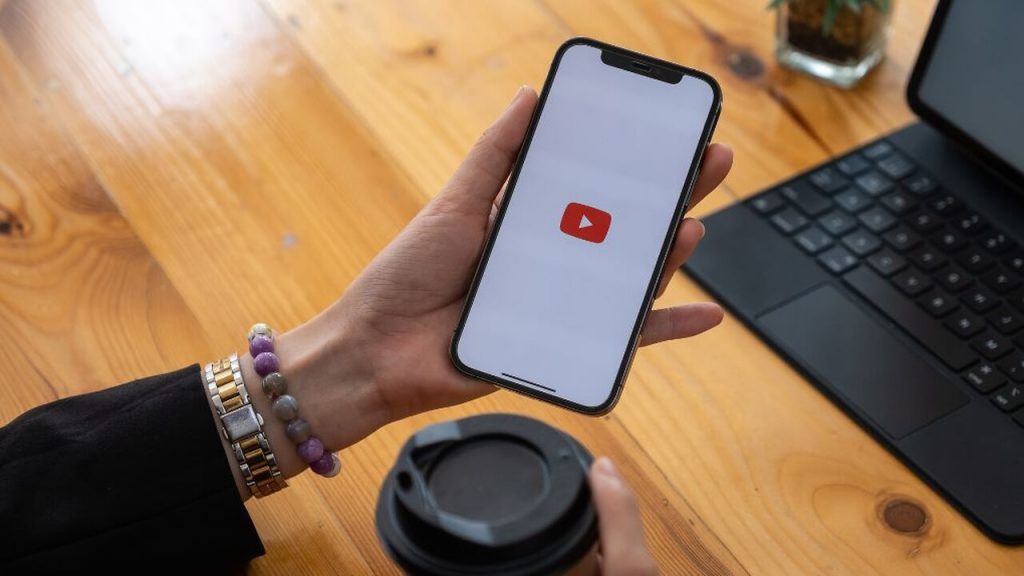  a hand holding a phone that shows the YouTube logo