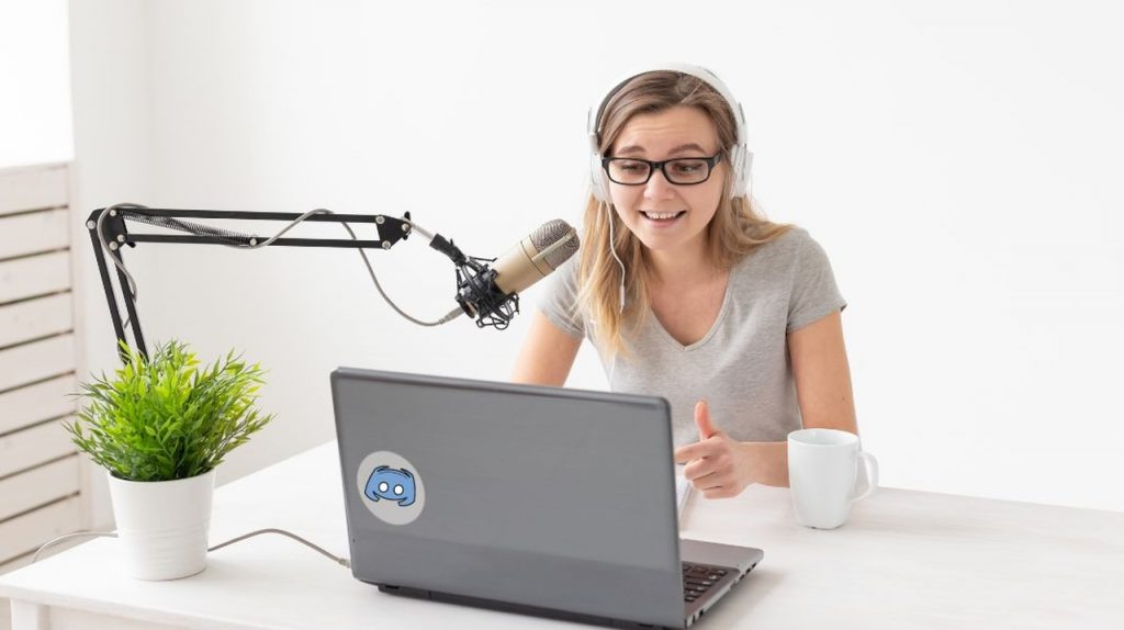 An image of a woman looking at the computer while talking into a microphone