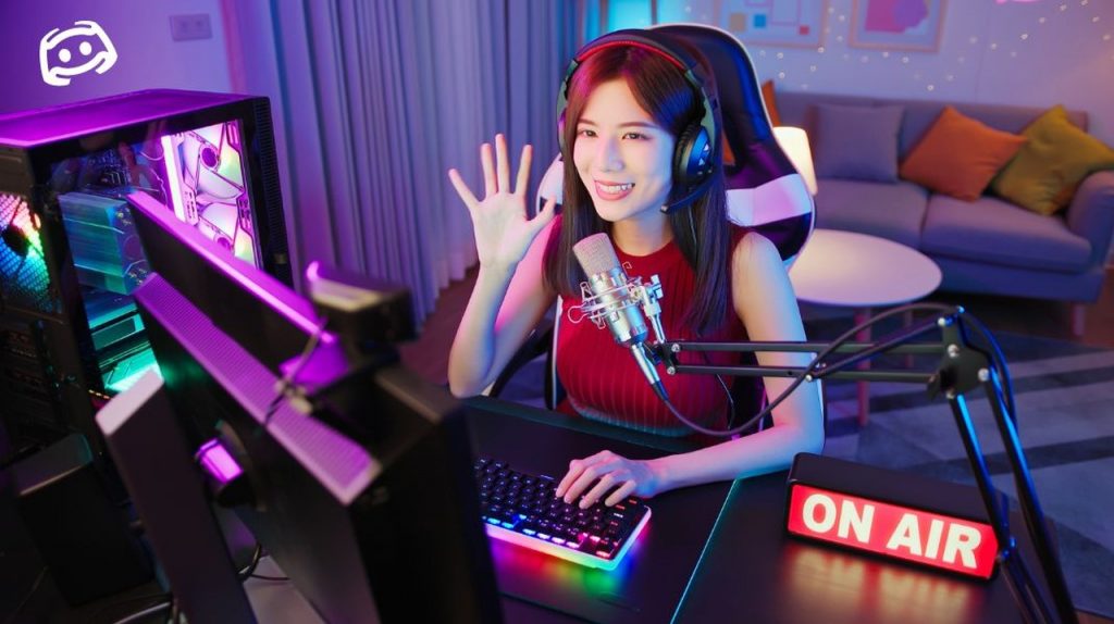 Picture of a smiling girl sitting in front of a computer and wearing headphones on her head