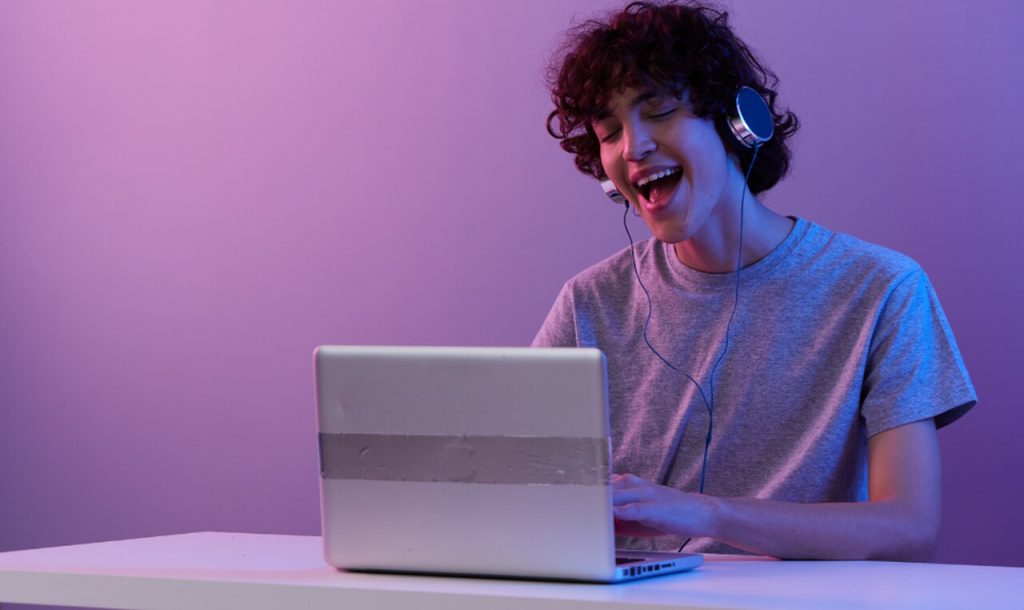 a happy twitch streamer listening to the music on twitch on his laptop and watching stories on Twitch