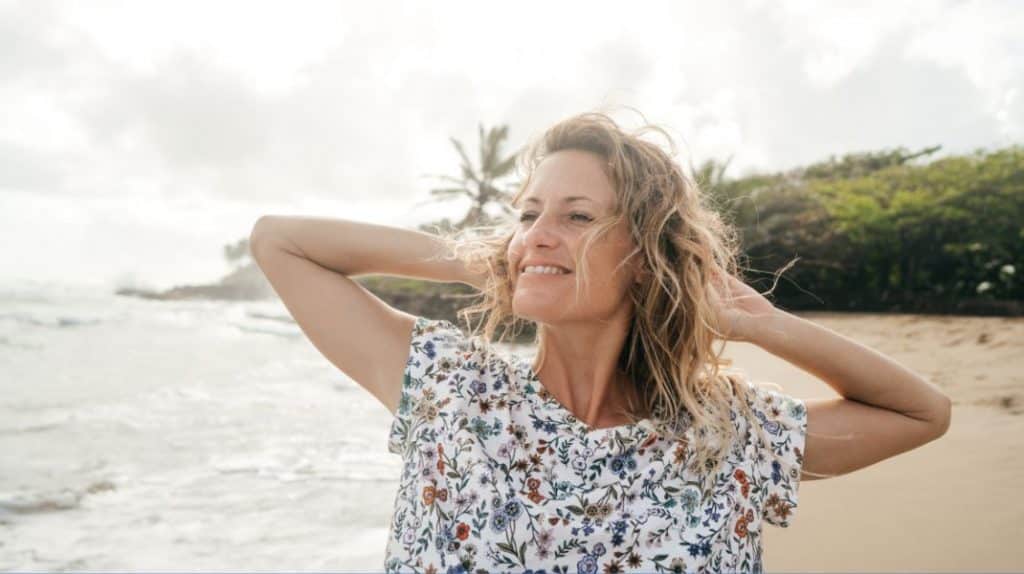Picture of a woman laughing with her hands behind her head on the beach